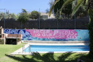 |||Pintura mural en un muro donde pone "Hacer lo que seas con lo que puedas" al lado de una piscina||||||||Imagen de Avioneta sobrevolando una playa tirando de un cartel publicitario que pone Mal es bien